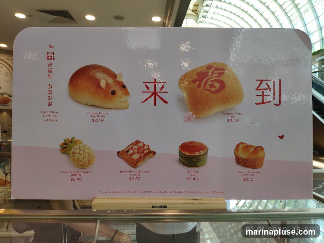 A display of various breads with festive names and designs, including a Golden Mouse bread, a Fortune Pillow bread with a Chinese character for fortune, a Prosperity Pineapple bread, a Berry Sweet Success pastry, Nian Gao, and a Yammy Treasure bread. Prices are listed for each item. The display also includes Chinese text and the BreadTalk logo.