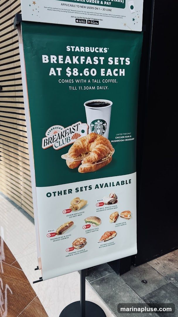 A promotional banner for Starbucks breakfast sets. The main offer is a breakfast set at $8.60, which includes a tall coffee and is available until 11:30 AM daily. A limited-time offer for a Chicken Ham & Mushroom Croissant is also featured. Below, various other breakfast sets are displayed with images and names, including Chicken Ham & Cheese Egg Crepe Wrap, Egg White, Roasted Pepper, Mushroom & Cheddar Wrap, Scrambled Egg & Cheese Brioche Sandwich, Scrambled Egg & Turkey Ham Pita, Rosemary Chicken & Emmental Cheese Croissant, and Egg Mayo & Cheese Multigrain Croissant.