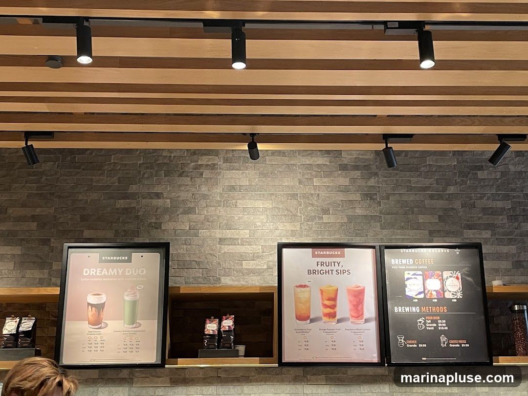 Three menu boards are displayed on a shelf. The left board advertises "Dreamy Duo" drinks. The middle board features "Fruity, Bright Sips" with three colorful beverages. The right board is for "Starbucks Reserve Brewed Coffee" and lists brewing methods and prices.