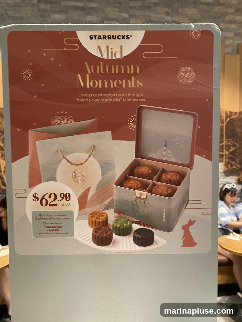 A promotional display for Starbucks Mid-Autumn Moments mooncakes. The display features a box of mooncakes, individual mooncakes, and a shopping bag. The price is $62.90 per box. Each box contains 8 pieces of mooncakes and can be chosen as ASSORTED or MIXED (Traditional + Assorted).