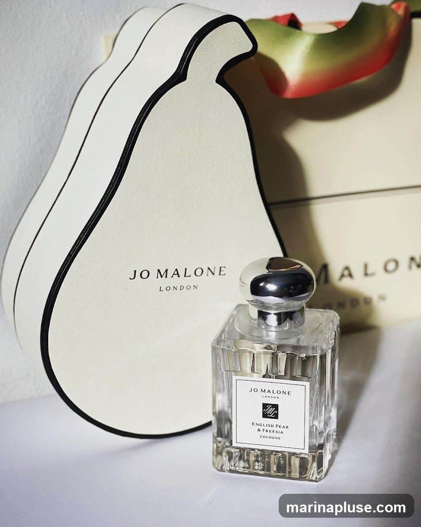 A bottle of Jo Malone English Pear & Freesia Cologne is displayed next to its pear-shaped gift box. The box has the Jo Malone London logo printed on it. Another Jo Malone London box is visible in the background.