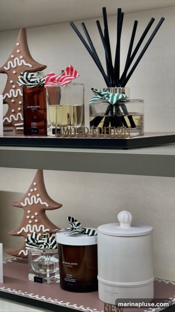 A festive display of Jo Malone products, including perfumes, a diffuser, and candles, decorated with gingerbread-themed Christmas trees and striped ribbons. The display features items labeled "Limited Edition" and "New."
