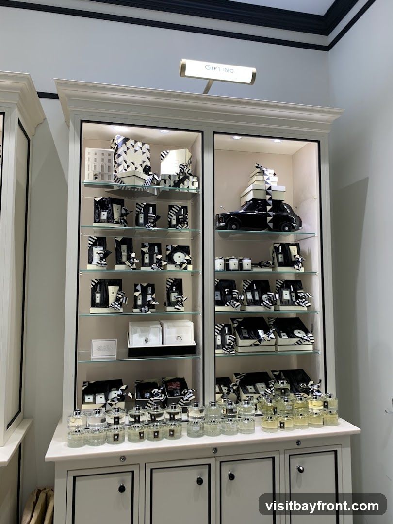 A display cabinet filled with various products, including perfumes, gift sets, and decorative items. The products are arranged on shelves and are predominantly in black and white packaging. A sign above the cabinet reads "GIFTING".