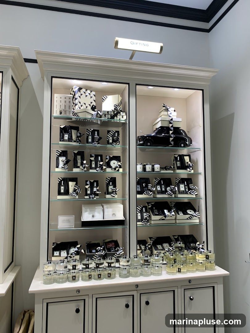 A display cabinet filled with various products, including perfumes, gift sets, and decorative items. The products are arranged on shelves and are predominantly in black and white packaging. A sign above the cabinet reads "GIFTING".