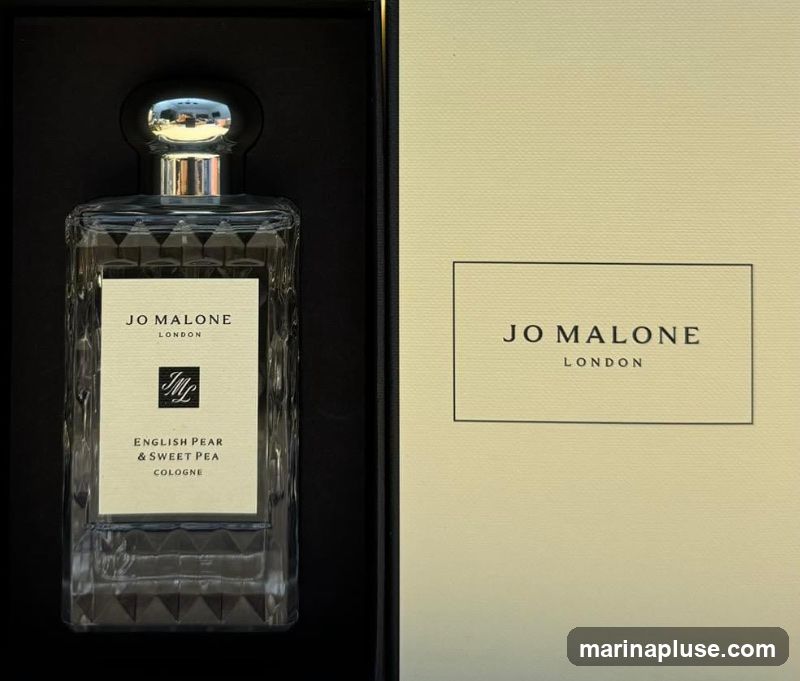 A bottle of Jo Malone English Pear & Sweet Pea Cologne is displayed in its packaging. The bottle is clear glass with a textured design and a silver cap. The label on the bottle reads "JO MALONE LONDON" and "ENGLISH PEAR & SWEET PEA COLOGNE". The packaging box is a pale yellow with the Jo Malone London logo printed on it.