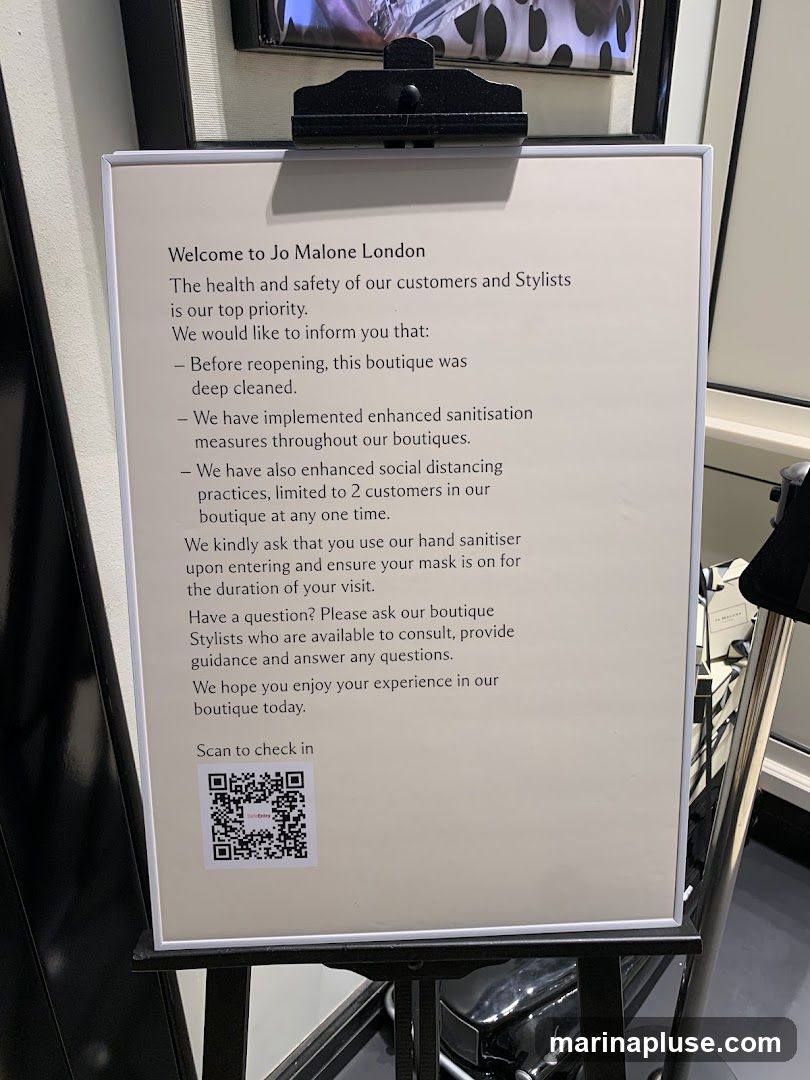 A sign welcomes customers to Jo Malone London and outlines health and safety measures for reopening, including enhanced sanitization, social distancing, and hand sanitizer use. It also provides information on asking boutique stylists for assistance and a QR code for check-in.