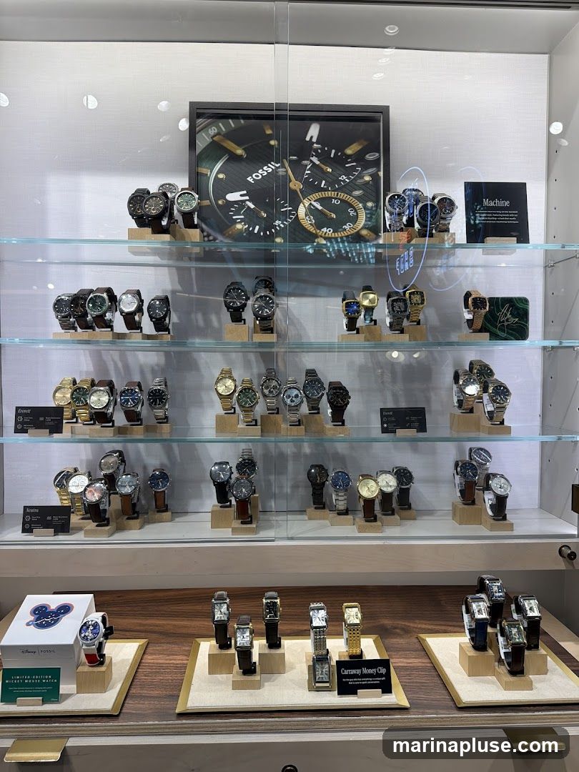 A display case filled with Fossil watches. The top shelf features a large framed image of a Fossil watch face and several watches. The middle shelves showcase various styles of watches, organized by collection. The bottom shelf displays a limited edition Mickey Mouse watch and a collection of money clips.