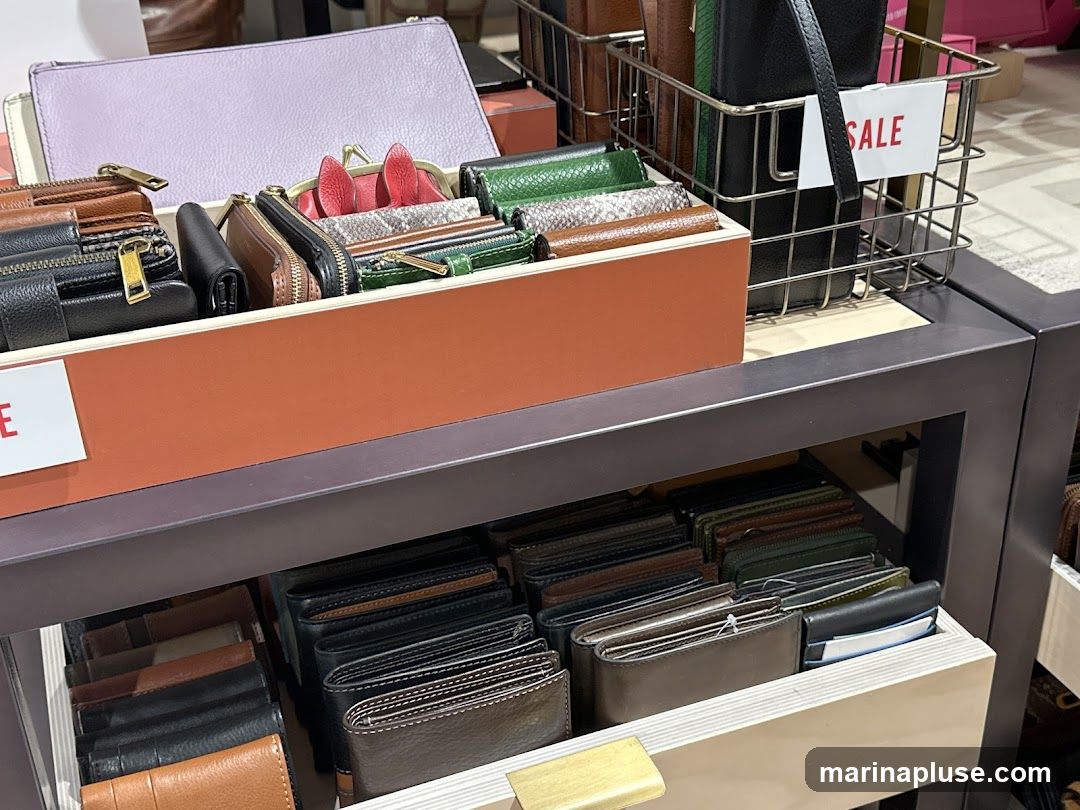 A display of various wallets and small leather goods, including zipped pouches, cardholders, and bi-fold wallets, arranged on shelves and in a wire basket. A sign indicating 'SALE' is visible in the basket.