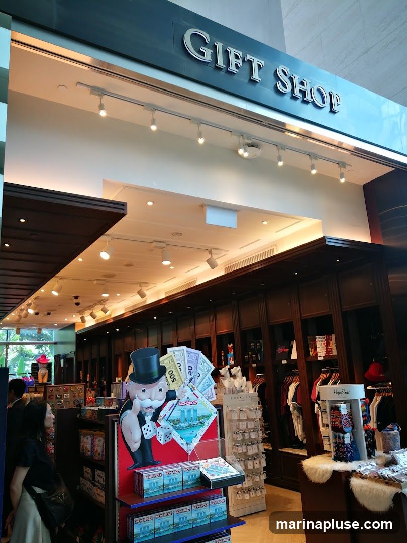 The exterior of a gift shop with the words "GIFT SHOP" prominently displayed above the entrance. Inside, various merchandise is visible, including Monopoly-themed displays, clothing racks, and shelves stocked with items.