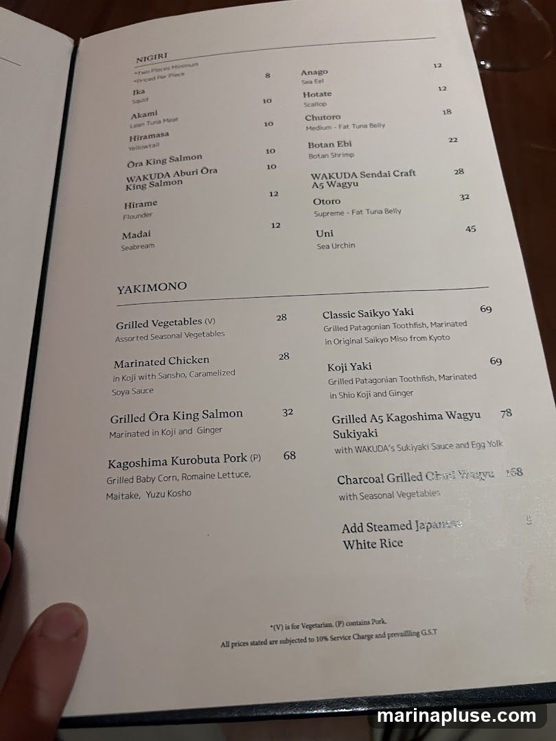 A menu with Nigiri and Yakimono sections. Nigiri includes items like Ika, Akami, Hiramasa, Ora King Salmon, Hirame, Madai, Anago, Hotate, Chutoro, Botan Ebi, WAKUDA Sendai Craft A5 Wagyu, Otoro, and Uni. Yakimono includes Grilled Vegetables, Marinated Chicken, Grilled Ora King Salmon, Kagoshima Kurobuta Pork, Classic Saikyo Yaki, Koji Yaki, Grilled A5 Kagoshima Wagyu Sukiyaki, and Charcoal Grilled Chad Wagyu.