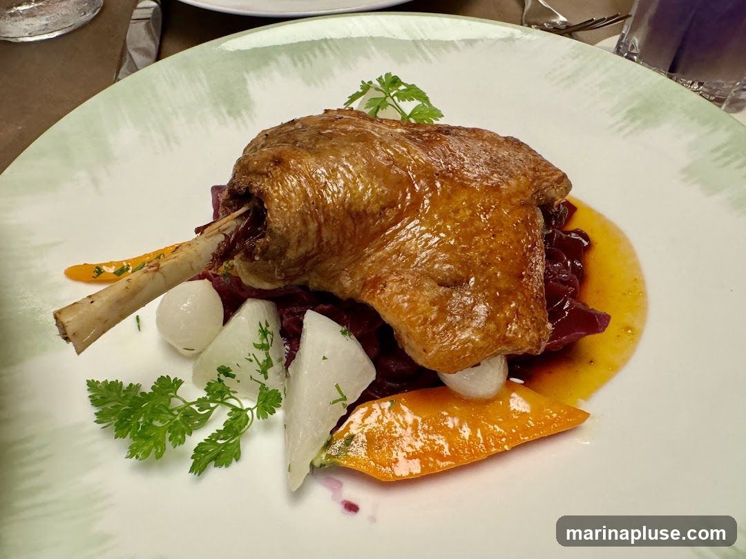 A close-up shot of a plate of food featuring a crispy duck confit leg served atop a bed of shredded red cabbage. Accompanying the duck are pieces of white turnip or radish, small pearl onions, and slices of cooked carrot. The dish is garnished with fresh parsley and sits on a white plate with a light green, abstract pattern around the rim. A glossy sauce surrounds the duck leg.