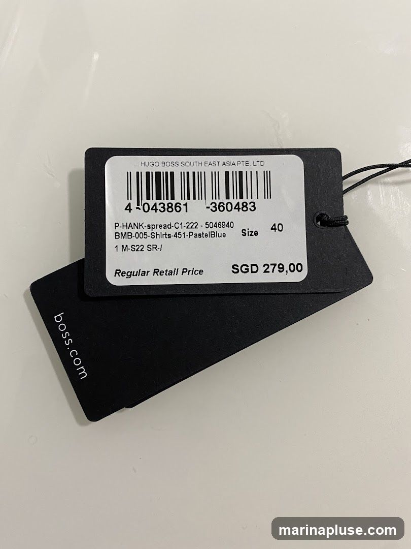 A product tag for Hugo Boss, showing product details and price. The tag includes a barcode, product code, size, and the price SGD 279,00. The website boss.com is also visible on a separate black tag.