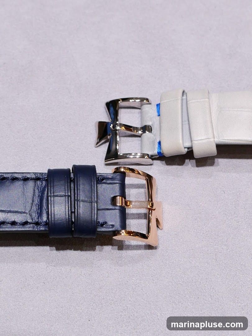 Two watch straps are shown, one navy blue and one light gray. Both straps have textured leather and metal buckles. The navy strap has a rose gold buckle, and the gray strap has a silver buckle.