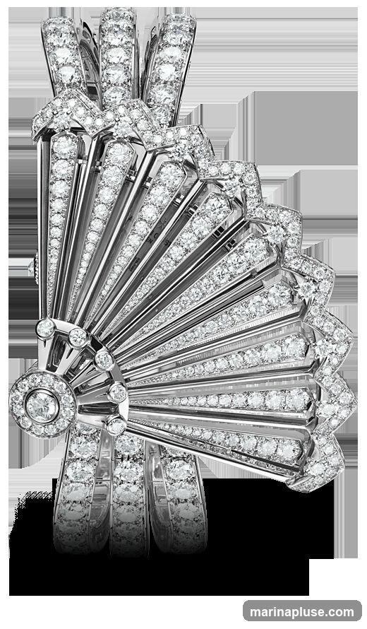A close-up studio shot of a luxurious bracelet designed to resemble a fan. The bracelet is heavily adorned with numerous small, brilliant-cut diamonds set in white metal, likely platinum or white gold. The fan motif is detailed, with radiating lines of diamonds and a central circular element also featuring diamonds. The bracelet band is composed of multiple parallel segments, each also encrusted with diamonds. The background is solid black, emphasizing the sparkle and intricate design of the jewelry.