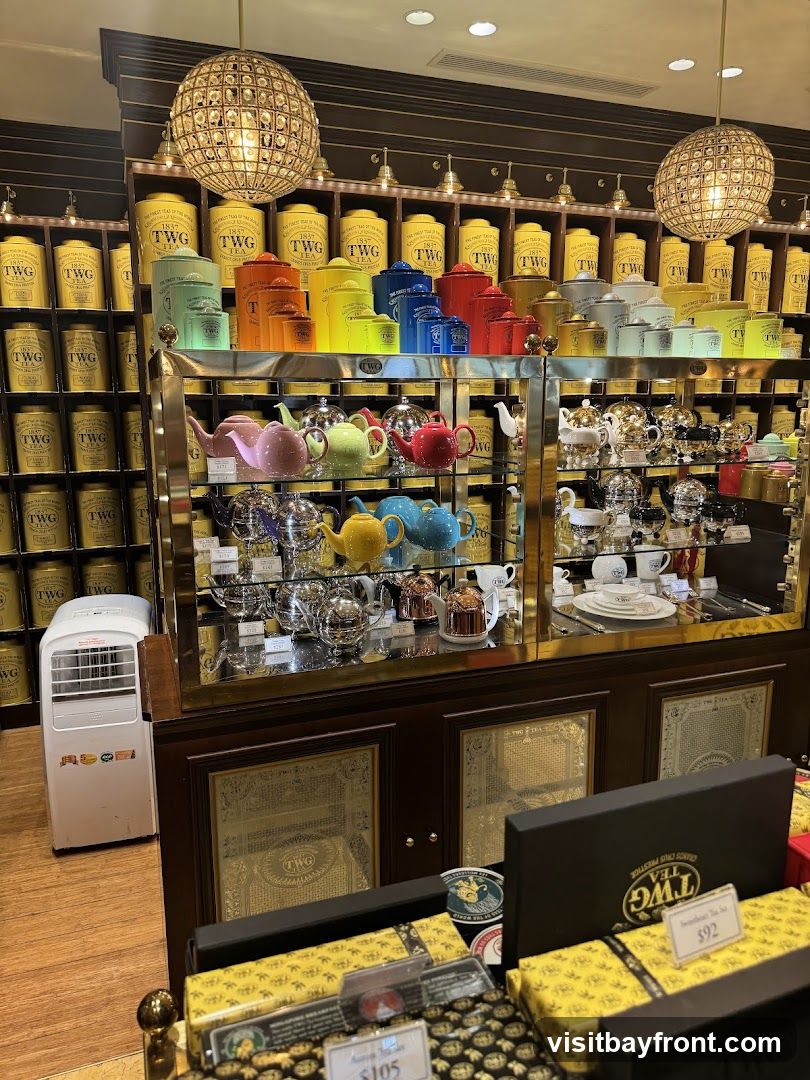 A display of tea canisters and teapots in a shop. The canisters are arranged on shelves and are in various colors, including yellow, green, orange, blue, and red. Below the canisters, teapots in different colors and styles are displayed. In the foreground, gift boxes with yellow packaging and black ribbons are visible, some with price tags. A portable air conditioning unit is on the left side of the image.