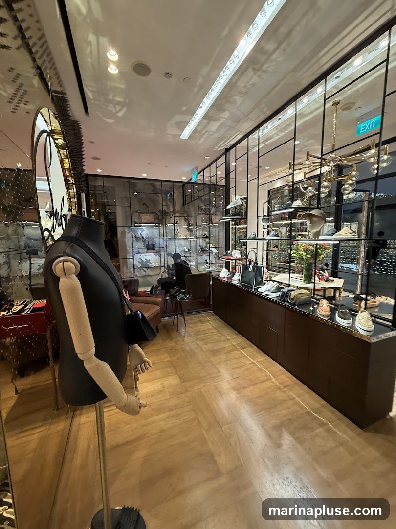 A well-lit interior of a luxury shoe store. A mannequin stands in the foreground, displaying a handbag. Shelves behind glass display various shoes and accessories. The floor is made of polished wood. An 'EXIT' sign is visible in the background.