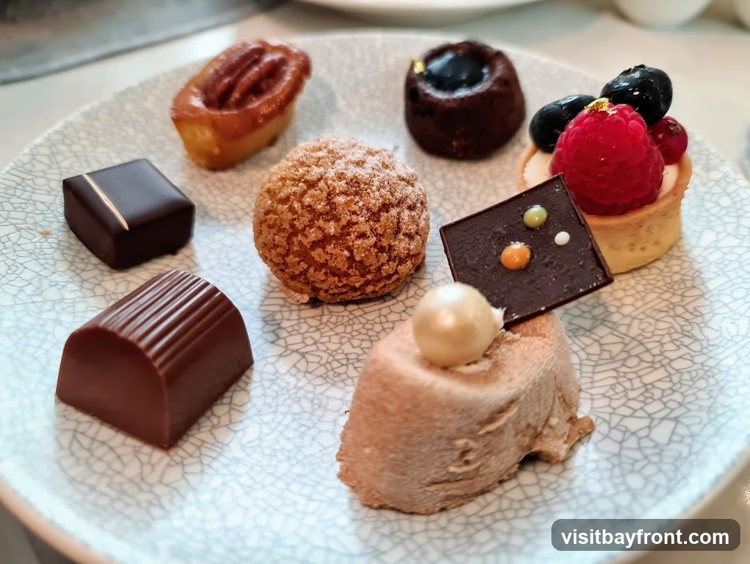 A plate of assorted pastries including chocolates, a tart with berries, a choux pastry, a pecan tart, and other small cakes.