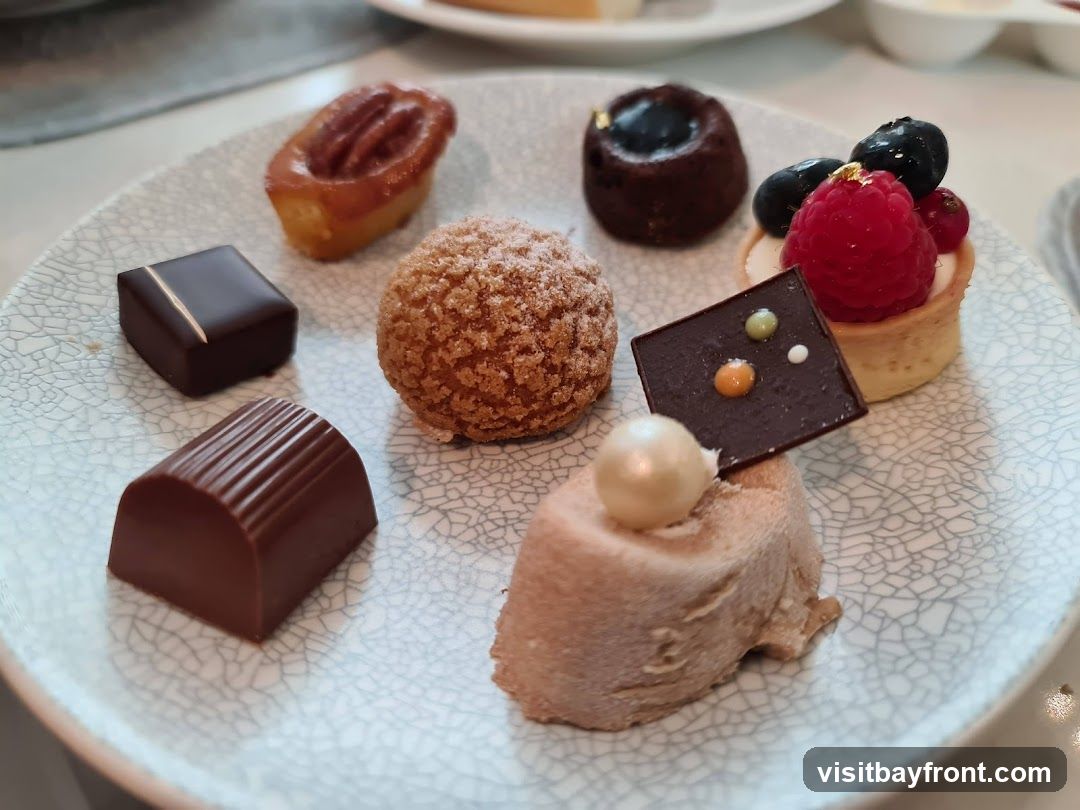 A plate of assorted pastries and chocolates, including a pecan tart, a chocolate cake, a fruit tart with berries, a cream puff, and various chocolate confections.