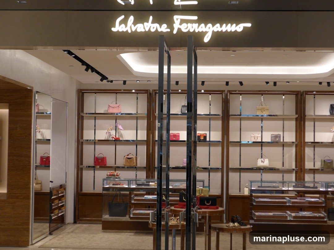 The exterior of a Salvatore Ferragamo store. The store features a well-lit interior with shelves displaying handbags and shoes. The brand name is prominently displayed in illuminated script above the entrance.