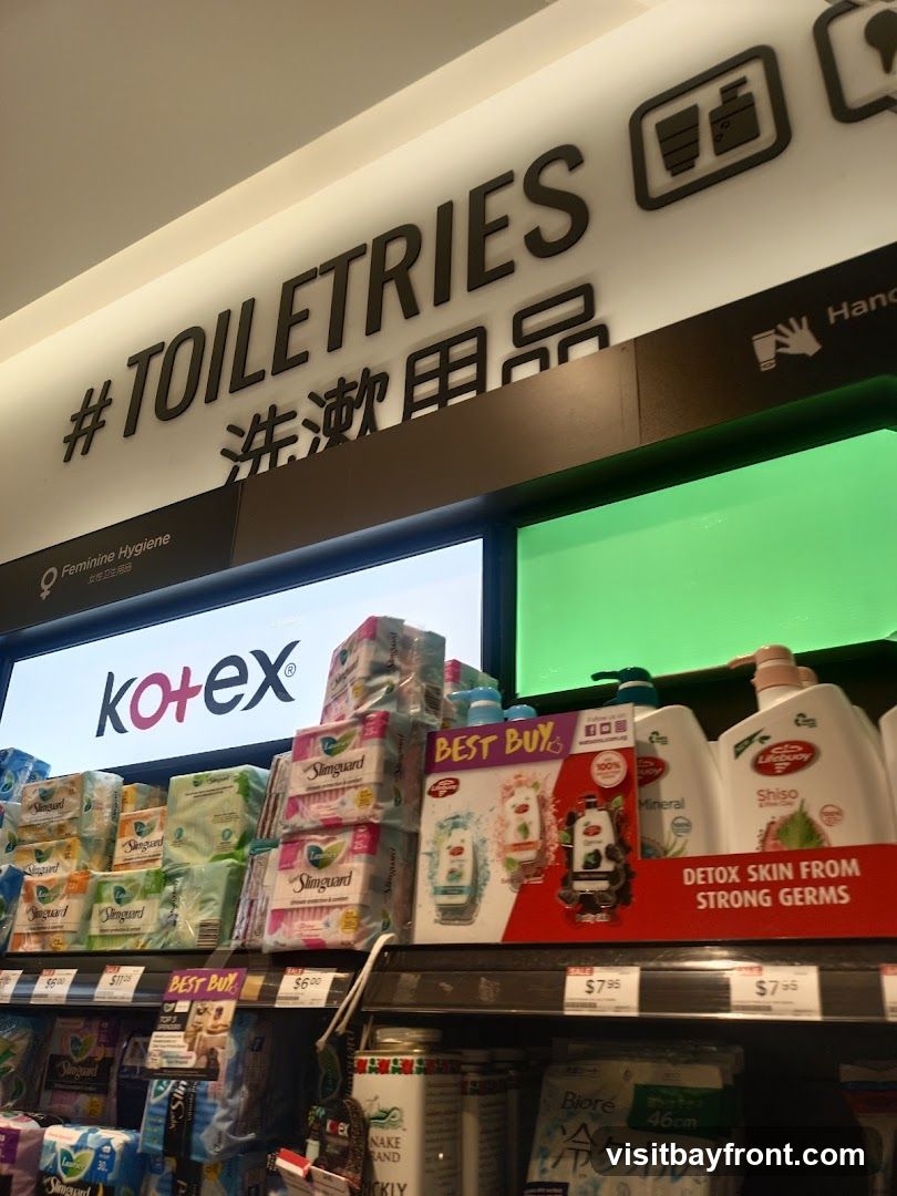 A shelf display in a store featuring various toiletries, including Kotex feminine hygiene products and Lifebuoy body wash. The aisle is labeled "#TOILETRIES" with Chinese characters below. Several products are marked as "BEST BUY".