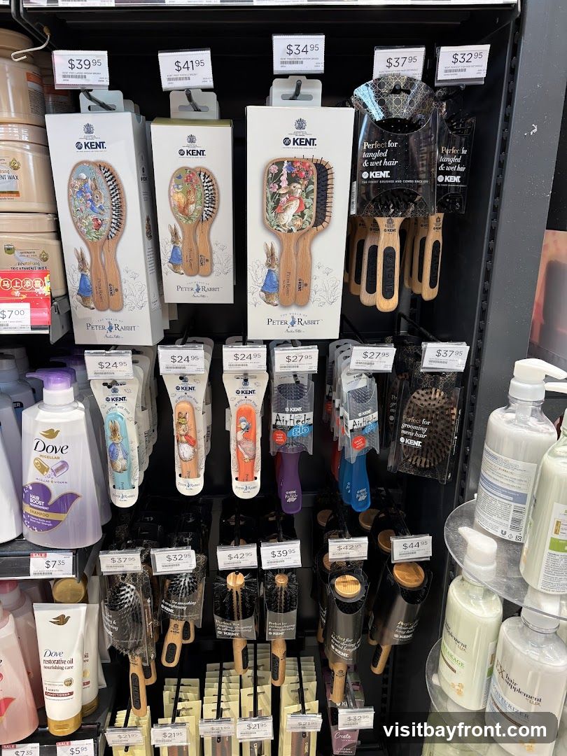 A retail display featuring various hair brushes, including those with Peter Rabbit designs and Kent brushes for tangled and wet hair. Also visible are bottles of Dove shampoo and conditioner, and other hair care products. Prices are displayed for many items.