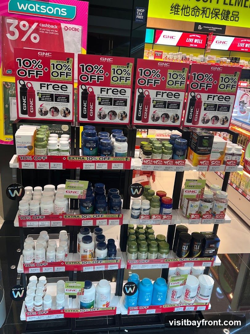 A retail display featuring various health supplements and promotional signage. The display includes bottles of vitamins, fish oil, probiotics, and other wellness products. Several signs advertise "10% OFF" and "EXTRA 10% OFF" with offers for free thermal water bottles for GNC members. Products are arranged on shelves with price tags. A Watsons logo is visible in the upper left corner.
