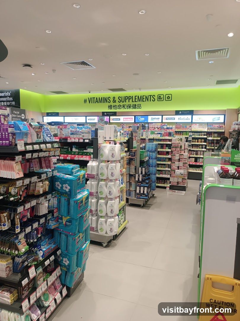 An aisle in a store stocked with various health and beauty products, including vitamins, supplements, facial care items, and feminine hygiene products. The aisle is brightly lit with a green accent wall displaying '#VITAMINS & SUPPLEMENTS' in English and Chinese. Shelves are filled with packaged goods, and a 'Caution Wet Floor' sign is visible in the foreground.