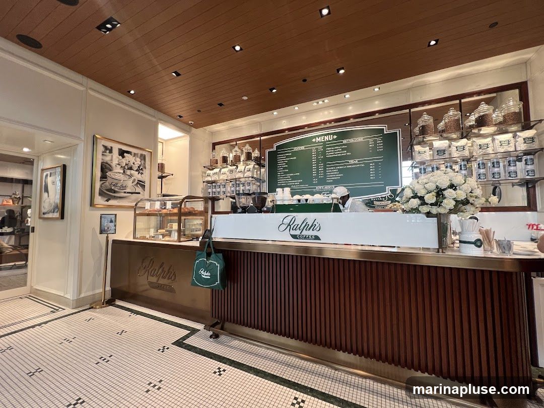 A view of the interior of Ralph's Coffee, showing the counter area with a menu board, display cases with pastries, and coffee supplies. The counter has the Ralph's Coffee logo prominently displayed.
