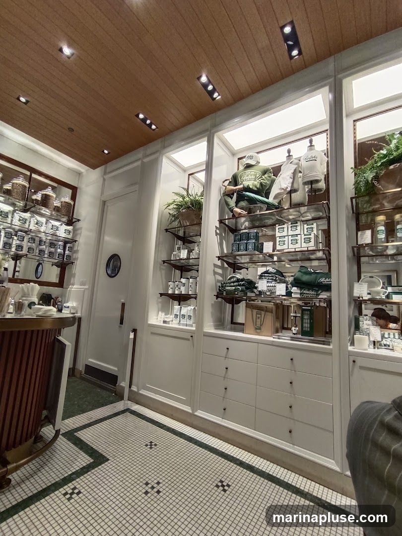 The image shows the interior of a store with shelves displaying various products. On the left, jars and packaged goods are visible on shelves. In the center and right, mannequins are dressed in branded apparel, including sweatshirts and hats. Packaged items, possibly skincare or food products, are also displayed on shelves and in drawers. The store features a wooden ceiling and tiled flooring.