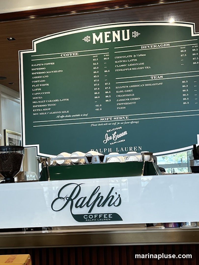A green menu board displays coffee, beverages, and tea options. Below the menu is a white counter with the Ralph's Coffee logo.