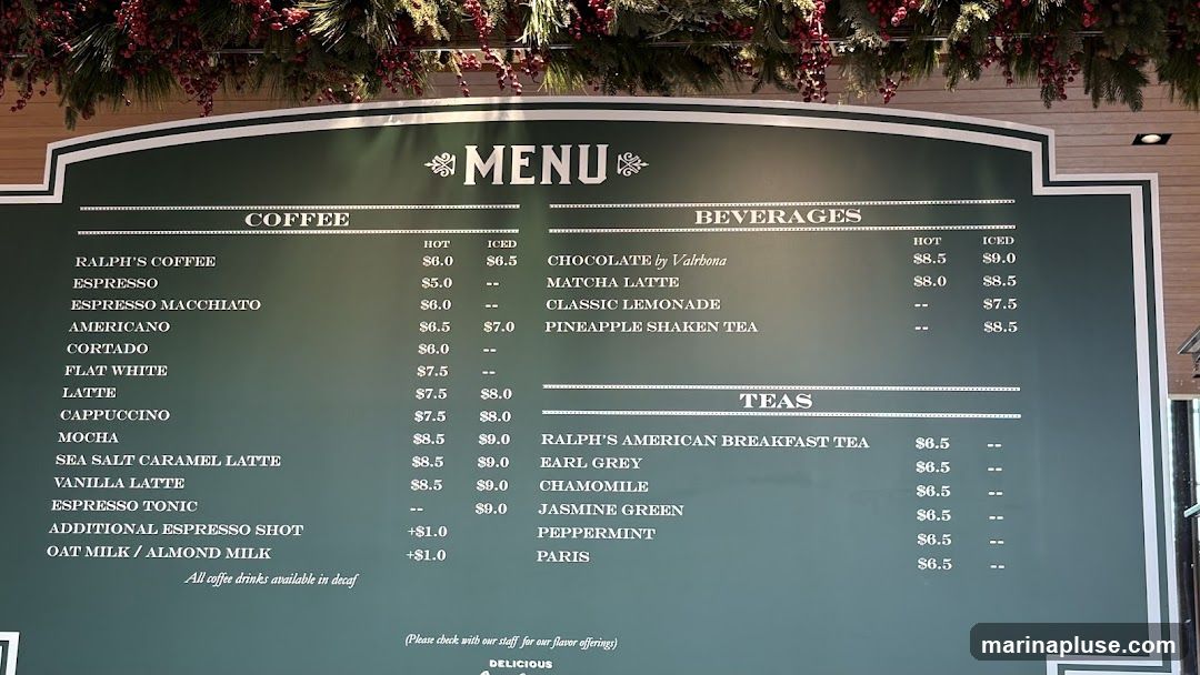 A dark green menu board with white text, featuring sections for Coffee, Beverages, and Teas. Decorative elements resembling snowflakes and pine branches are visible at the top.