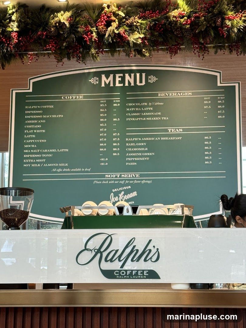 A green menu board displays coffee, beverages, and teas with prices. Below the menu, there is a soft serve ice cream section and the Ralph's Coffee, Ralph Lauren logo.