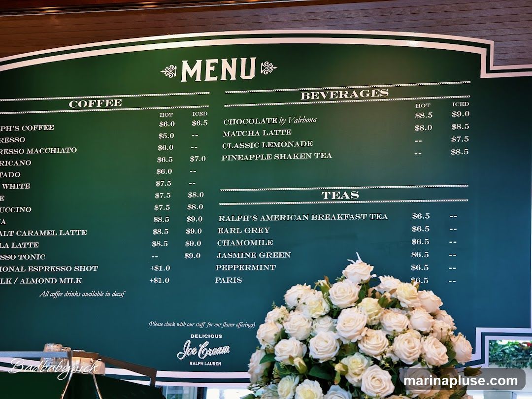 A green menu board with white text listing coffee, beverages, and teas. Below the menu, there is a sign for "Delicious Ice Cream" by Ralph Lauren. A bouquet of white roses is in the foreground.