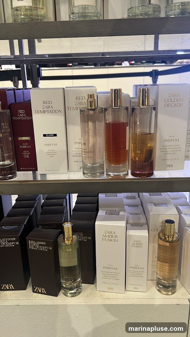 A retail display featuring various Zara perfumes. The top shelf shows bottles of Zara Golden Decade and Red Zara Temptation. The bottom shelf displays more bottles and boxes of Zara perfumes, including Zara Amber Fusion and Zara Hypnotic Poison.