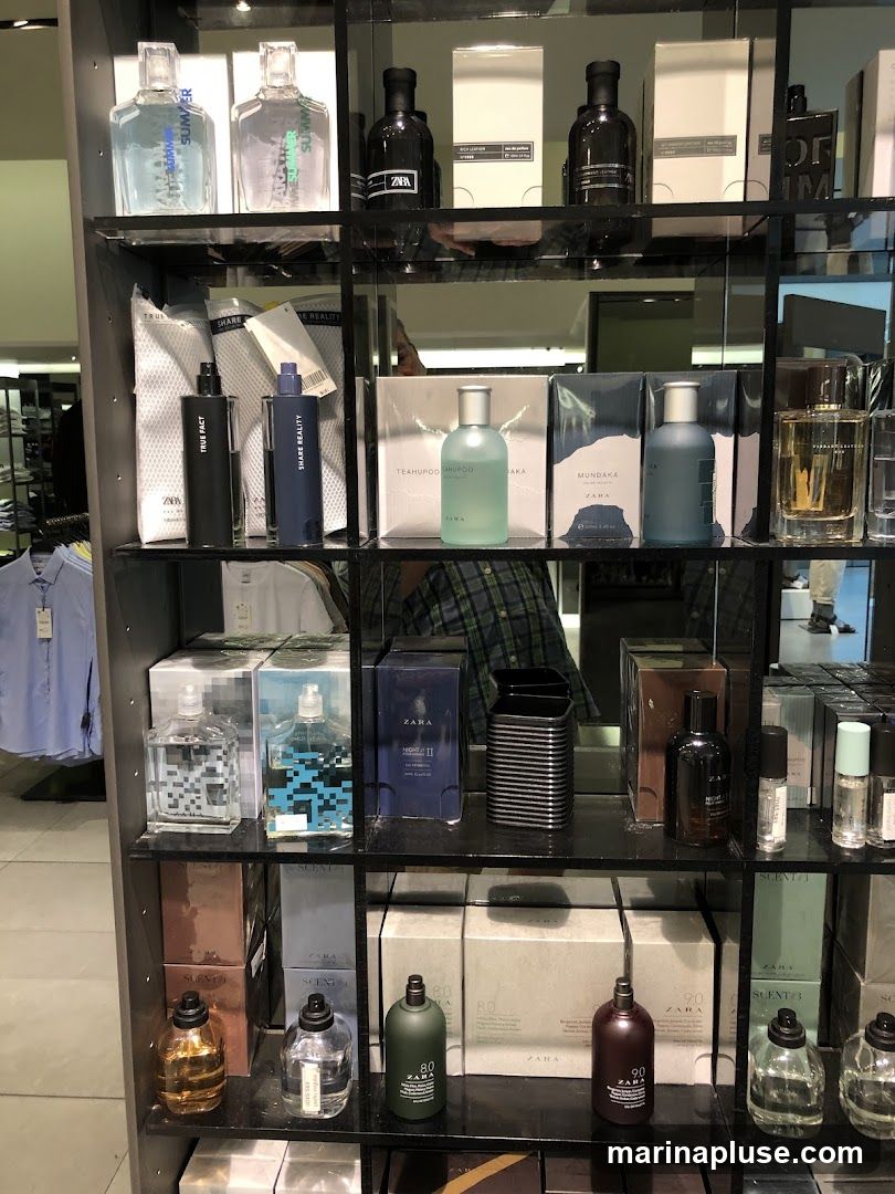 A display shelf filled with various bottles of perfume and cologne. The bottles are arranged on multiple shelves, with some in boxes and others displayed individually. The branding "ZARA" is visible on many of the products.