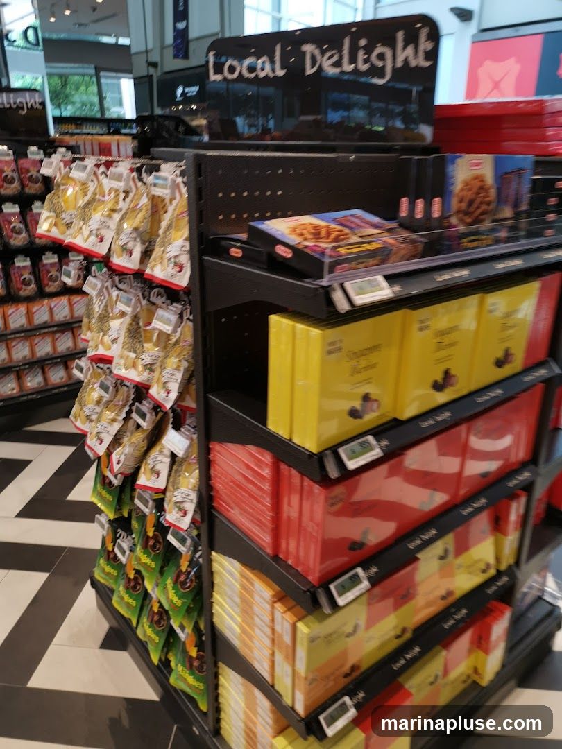 A display of packaged snacks and sweets on shelves in a store. The top shelf has a sign that says "Local Delight". There are bags of snacks hanging on the left and boxes of sweets on the right. The floor has a black and white zigzag pattern.