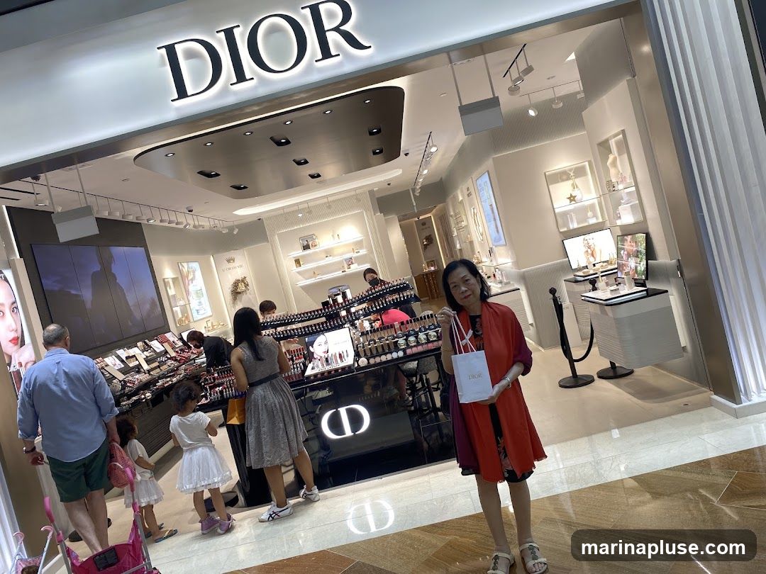 A family is shopping at a Dior cosmetics store. The store has a large DIOR sign above the entrance. Inside, there are displays of makeup and skincare products. A woman is holding a Dior shopping bag.
