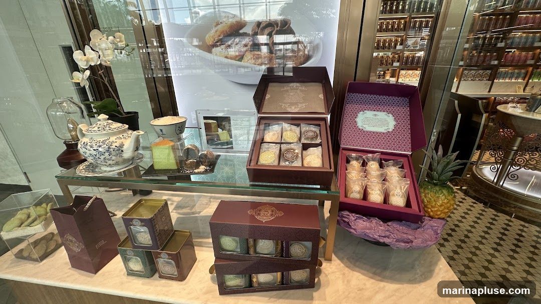 A display of various desserts and gift boxes, including cakes, cookies, and tea sets. A decorative pineapple is also visible.