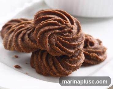 A close-up shot of several chocolate swirl cookies stacked on a white plate.