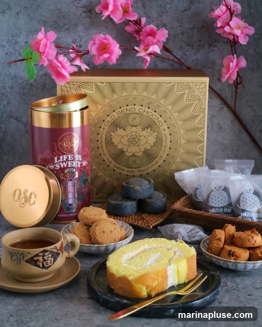 A collection of traditional Chinese snacks, including cookies, a swiss roll, and pineapple tarts, are arranged with a tin of tea and a teacup. The items are presented against a grey, textured background, with pink artificial flowers adding a decorative touch. The packaging and tin feature the brand "OLD SENG CHOONG" and the slogan "LIFE IS SWEET".