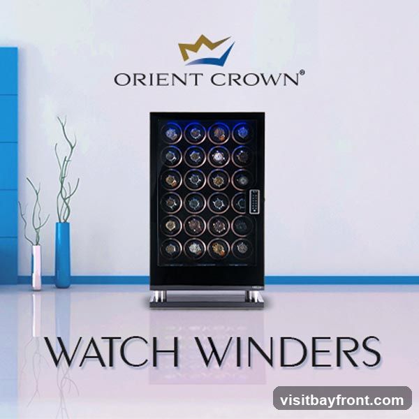 A display of watch winders with the Orient Crown logo above. The watch winders are in a black cabinet with blue interior lighting, and each compartment holds a watch. The text "WATCH WINDERS" is displayed prominently at the bottom.