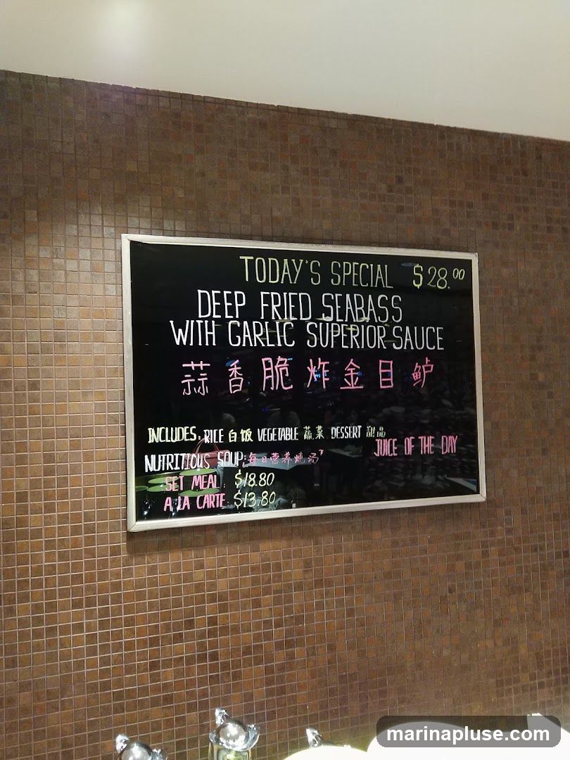 A menu board displaying today's special, which is Deep Fried Seabass with Garlic Superior Sauce. It also lists inclusions, a nutritious soup, a set meal, a la carte options, and juice of the day.
