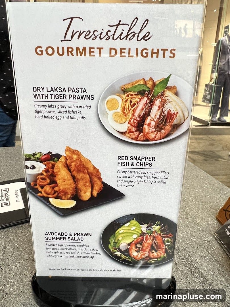 A menu board displaying three gourmet dishes: Dry Laksa Pasta with Tiger Prawns, Red Snapper Fish & Chips, and Avocado & Prawn Summer Salad.