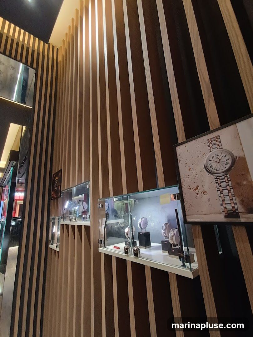 A wall with vertical wooden slats displays several glass cases filled with watches. A framed advertisement for a watch is also visible on the wall.