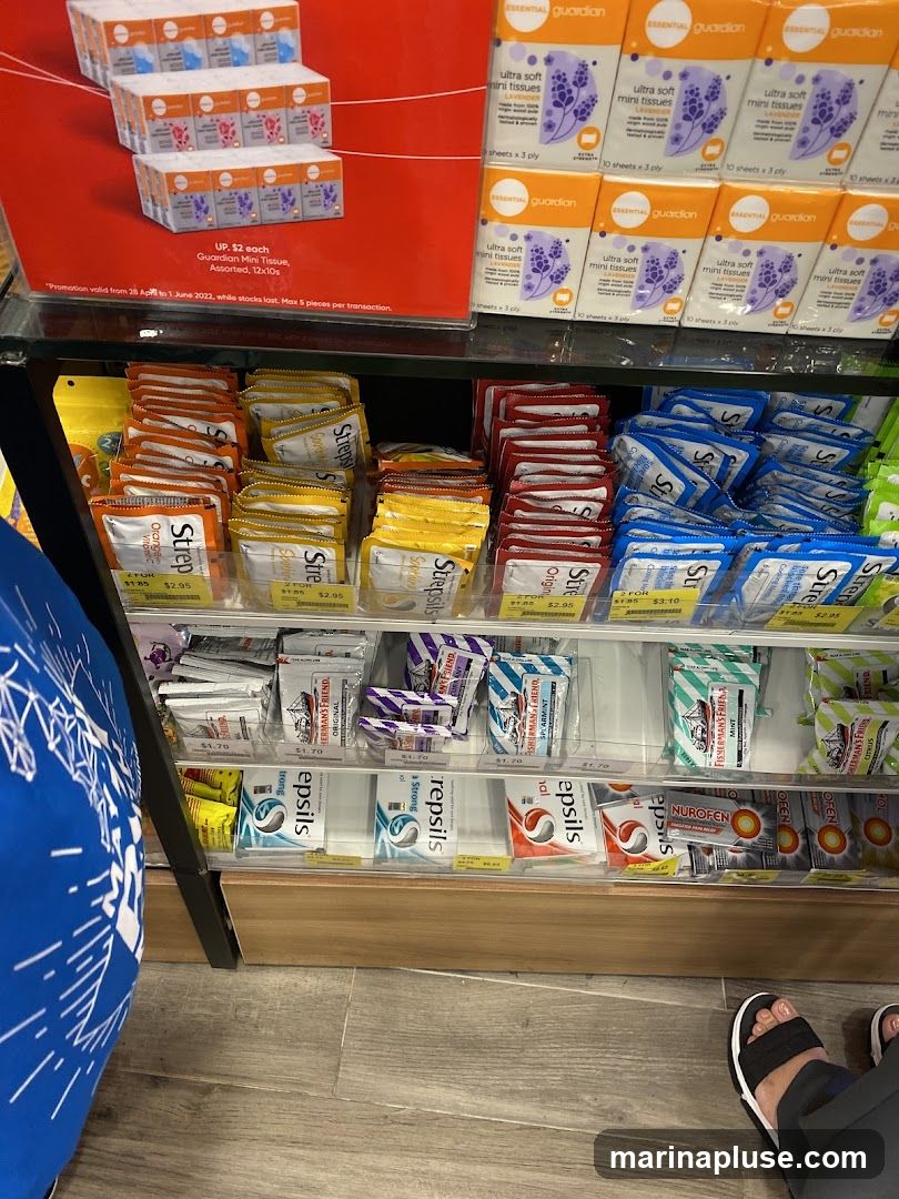A display shelf stocked with various brands of tissues and lozenges. At the top, promotional signage advertises Guardian Mini Tissues for $2 each. Below, shelves are filled with packets of Strepsils in different flavors like Orange, Original, and Citrus, as well as Fisherman's Friend lozenges. Nurofen pain relief tablets are also visible.