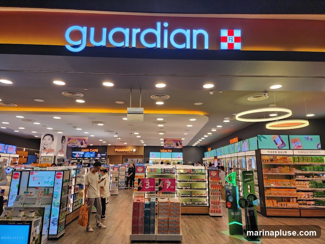 The exterior of a Guardian pharmacy with its prominent blue neon sign and red and white RX logo. Inside, shelves are stocked with health and beauty products, including hair care, vitamins, and pharmacy items.
