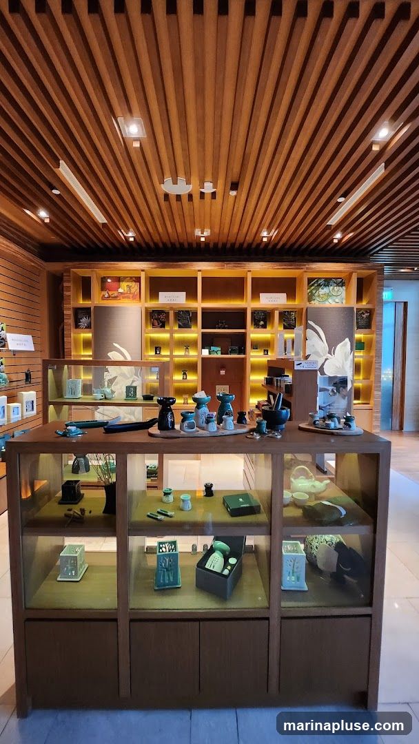 A well-lit retail display featuring various ceramic items, including incense burners, tea sets, and decorative pieces. The items are arranged on wooden shelves and within glass display cases. The ceiling is made of wooden slats with integrated lighting.