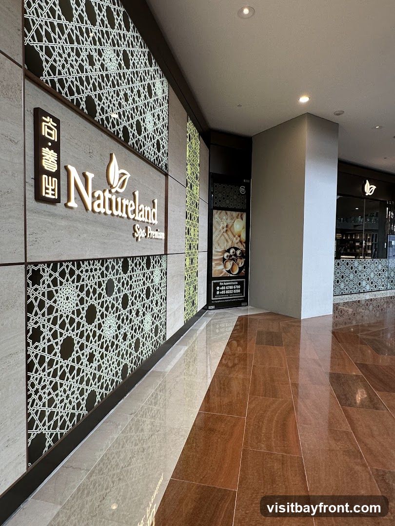 The exterior of a spa with a prominent sign that reads "Natureland Spa Premium". The wall features intricate geometric patterns. To the right, a door is visible with a poster displaying spa services and contact information.