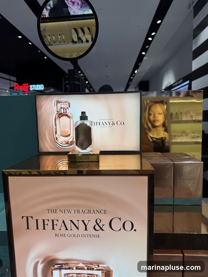 A display featuring Tiffany & Co. Rose Gold Intense fragrance. The display includes promotional images of the perfume bottles, boxes of the fragrance, and a portrait of a woman. The background shows a retail environment with shelves and lighting.