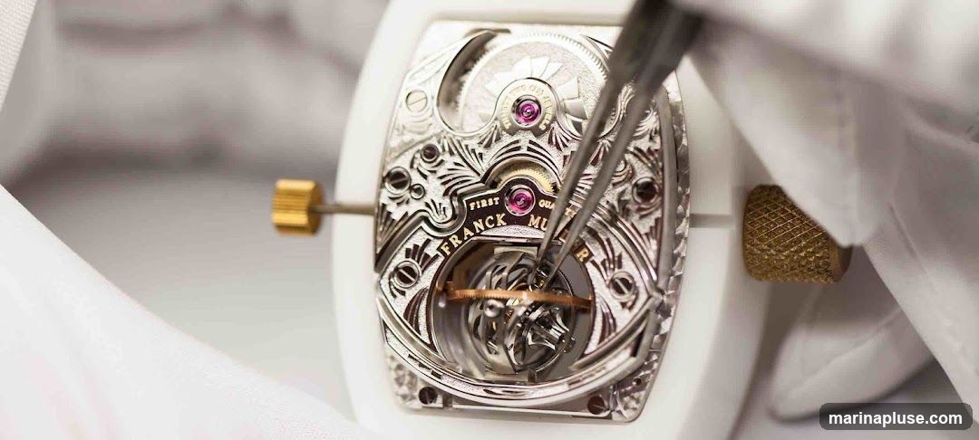 A close-up shot shows a watchmaker's hands using tweezers to meticulously assemble the intricate internal mechanism of a Franck Muller watch. The movement features detailed engraving and visible jewels.